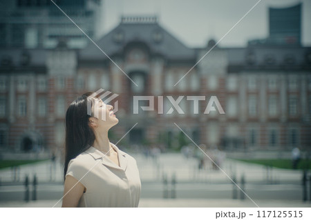 夏の強い日差しのなか空を見上げる若い女性 夏の強い日差しのなか空を見上げる若い女性 117125515