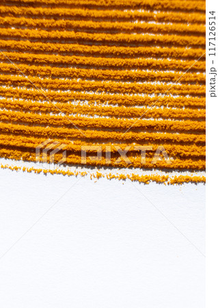 Abstract striped orange background of spilled turmeric on white background. Abstract striped orange background of spilled turmeric on white background. 117126514