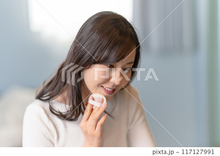 パフを使ってメイクする笑顔の女性 117127991