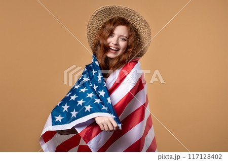 Smiling woman with national USA flag on beige background. American patriot, 4th of July - Independence day celebration, election, America, labor. US banner. Smiling woman with national USA flag on beige background. American patriot, 4th of July - Independence day celebration, election, America, labor. US banner. 117128402
