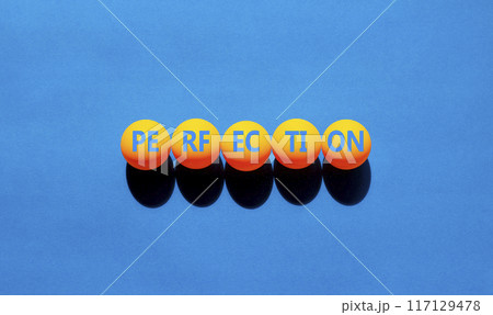 Perfection symbol. Concept word Perfection on beautiful yellow ping pong balls. Beautiful blue background. Business perfection concept. Copy space. 117129478