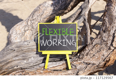 Flexible working symbol. Concept words Flexible working on beautiful yellow blackboard. Beautiful old tree sand background. Business flexible working concept. Copy space. Flexible working symbol. Concept words Flexible working on beautiful yellow blackboard. Beautiful old tree sand background. Business flexible working concept. Copy space. 117129567