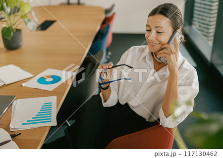A professional woman actively engaged in an important phone call in a modern office space 117130462