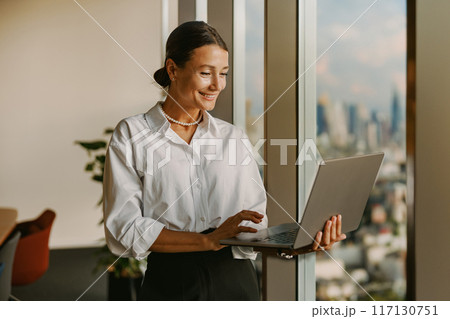 A Professional Woman Working Diligently on Her Laptop in a Modern Office Environment 117130751