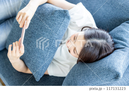 ソファーで寝転がってスマホを見る女性 ソファーで寝転がってスマホを見る女性 117131223