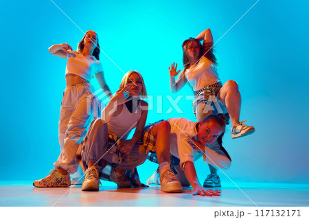 Four dancers, dressed in casual outfits, strike bold and energetic poses in neon lights, capturing their lively and fun-loving spirit. Four dancers, dressed in casual outfits, strike bold and energetic poses in neon lights, capturing their lively and fun-loving spirit. 117132171