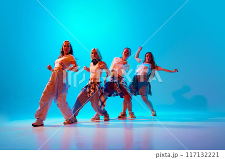 Lively group of four dancers in retro casual wear poses boldly under blue lighting, capturing their unique styles and dynamic energy. 117132221