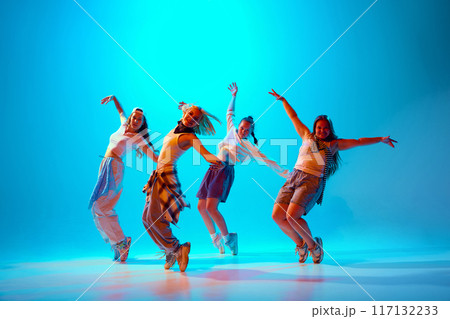 Group of artistic dancers, dressed in casual attire, pose confidently under vibrant blue lighting, highlighting expressive hip-hop moves. Group of artistic dancers, dressed in casual attire, pose confidently under vibrant blue lighting, highlighting expressive hip-hop moves. 117132233