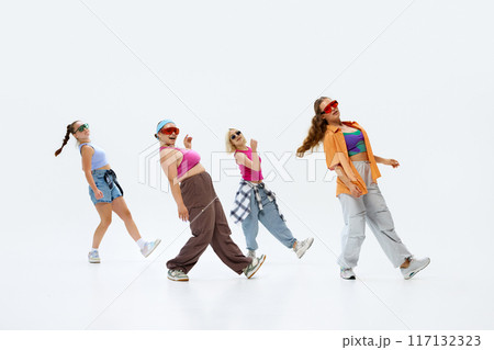 Dancers in trendy, colorful clothing and sunglasses strike coordinated pose, exuding confidence and flair against white studio background. 117132323