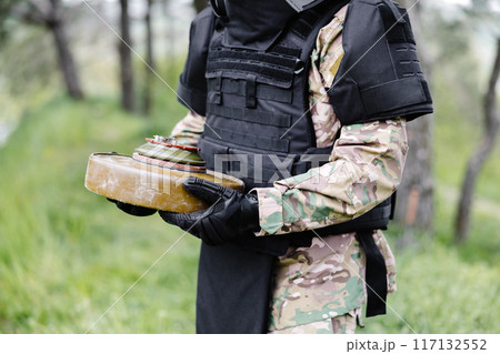 A man in a special suit works with a detector and found an explosive device. A man tries to neutralize an anti-tank mine 117132552