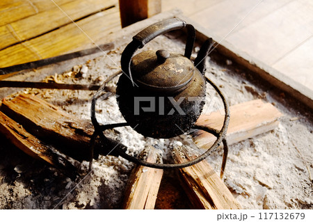 Old vintage dirty kettle teapot heating on firewood and charcoal stove for camping Old vintage dirty kettle teapot heating on firewood and charcoal stove for camping 117132679