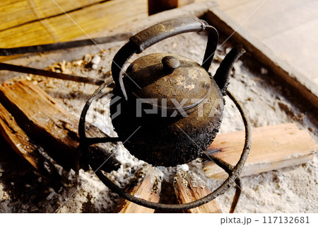 Old vintage dirty kettle teapot heating on firewood and charcoal stove for camping Old vintage dirty kettle teapot heating on firewood and charcoal stove for camping 117132681
