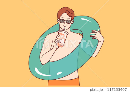 Man goes to beach and drinks cold cocktail, holding inflatable swimming ring in hand Man goes to beach and drinks cold cocktail, holding inflatable swimming ring in hand 117133407
