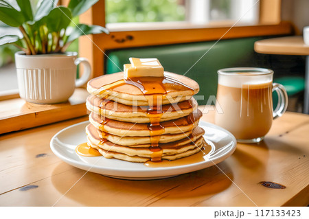 カフェのテーブルの上に置かれた、何枚も重ねられたパンケーキとカフェラテ。 117133423
