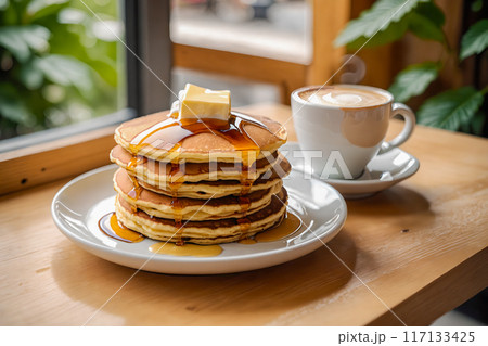 カフェのテーブルの上に置かれた、何枚も重ねられたパンケーキとカフェラテ。 117133425