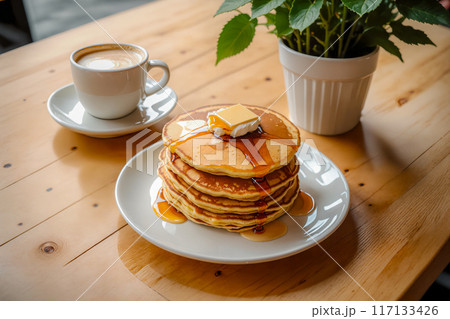 カフェのテーブルの上に置かれた、何枚も重ねられたパンケーキとカフェラテ。 117133426