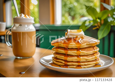 カフェのテーブルの上に置かれた、何枚も重ねられたパンケーキとカフェラテ。 117133428