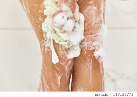 Woman washing her legs with foam bubbles and bath sponge while taking shower in the bathroom Woman washing her legs with foam bubbles and bath sponge while taking shower in the bathroom 117133772