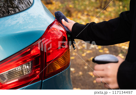 Closeup picture, image young woman, driver, dry wiping her car with microfiber cloth after washing it, cleaning auto, automobile windows. Transportation self service, care concept. Paint protection 117134497
