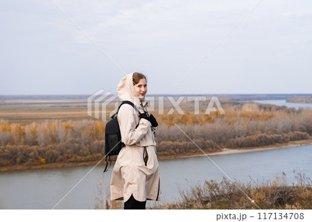 A woman stands on the edge of a cliff and looks at a nearby island, the sea. Unity with nature. A woman stands on the edge of a cliff and looks at a nearby island, the sea. Unity with nature. 117134708
