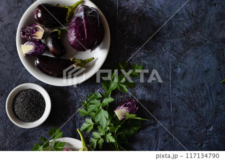 Assortment raw organic of purple vegetables mini eggplants, spring onion, beetroot, radicchio salad, plums, kohlrabi, flower salt over dark metal background. Top view with space. Food frame Assortment raw organic of purple vegetables mini eggplants, spring onion, beetroot, radicchio salad, plums, kohlrabi, flower salt over dark metal background. Top view with space. Food frame 117134790