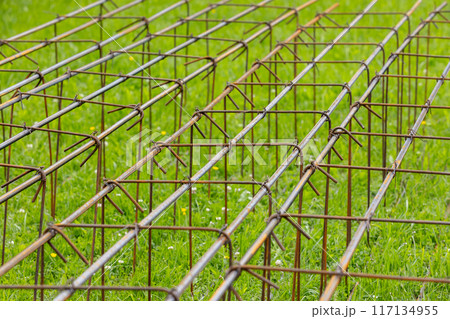 Reinforcement cages are on green grass at construction site, abstract 117134955