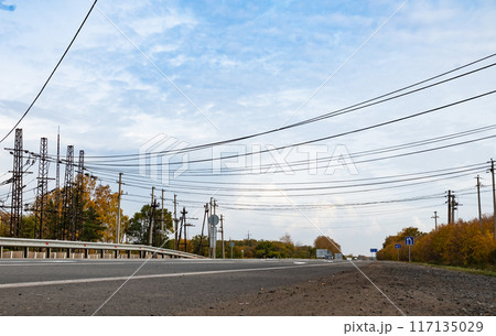 High voltage power lines leading through a green field. Transmission of electricity by means of supports through agricultural areas. 117135029