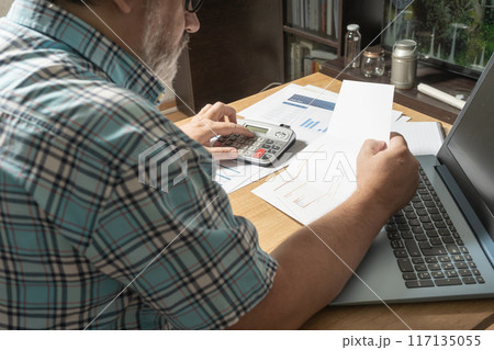 White man sitting with a sheet in his hands reviewing cash and money flows, projections and bills. Concept work at home, checking accounts, economy of the home. View to normal. 117135055