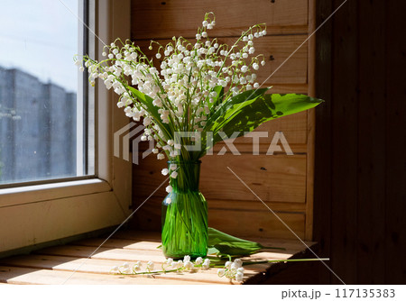 Lily of the valley flowers in glass vase, black background, selective focus 117135383