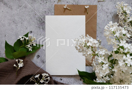 Composition with empty green envelope and beautiful spring lilac flowers on mint background. Mockup card invitation greeting card postcard copy space template. Branches of lilac blooming bouquet. 117135473