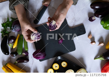 Woman cooking fresh salad with ripe red cabbage at grey table 117135708