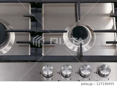 Front view of Contemporary tempered glass gas stove hob with Two burners with auto ignition knob on wooden countertop, cast iron pan supports fan hood and oven built in compact 117136455
