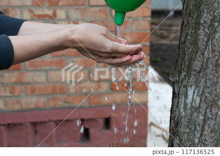 Washing hands after ground works in garden from garden tap Washing hands after ground works in garden from garden tap 117136525