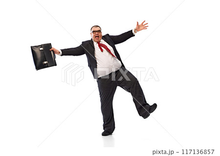 Happy and excited fat man, businessman in black suit, formal wear dancing emotionally with briefcase isolated on white background. Progress. Happy and excited fat man, businessman in black suit, formal wear dancing emotionally with briefcase isolated on white background. Progress. 117136857