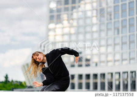 Young Dancer Performing Urban Dance Routine at Modern Cityscape During Overcast Afternoon 117137558