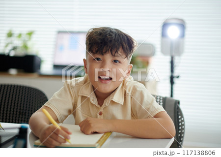 Smiling Child Writing in Modern Home Office Setting Smiling Child Writing in Modern Home Office Setting 117138806