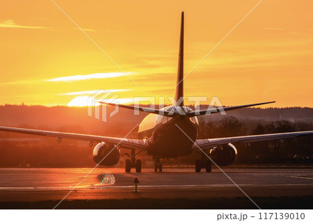 Airplane taxiing to airport runway at sunset . Airplane taxiing to airport runway at sunset . 117139010