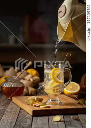 Hot water is poured into a glass for preparing ginger tea. 117139502