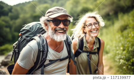 Middle aged couple walking on forest path with backpacks in summer 117139977