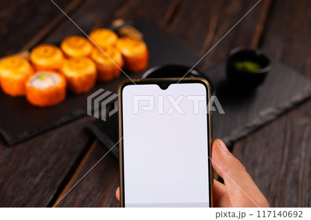 Hands taking picture of sushi japan food with smartphone. Copy space and empty space for advertising Hands taking picture of sushi japan food with smartphone. Copy space and empty space for advertising 117140692