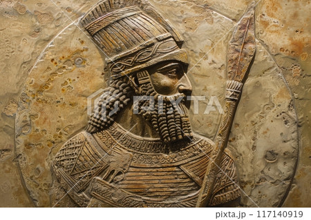 A proud Assyrian warrior stands ready, adorned in intricate armor, holding a spear, embodying strength and valor from a bygone era. A proud Assyrian warrior stands ready, adorned in intricate armor, holding a spear, embodying strength and valor from a bygone era. 117140919