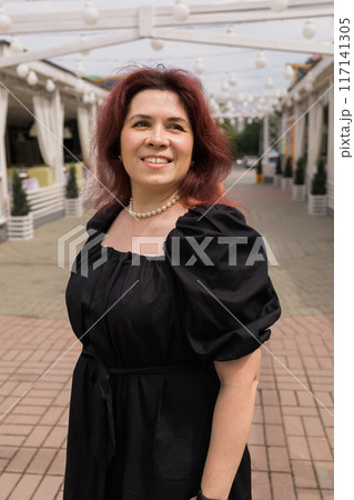 Confident overweight plus size woman walking on city street in black dress Confident overweight plus size woman walking on city street in black dress 117141305