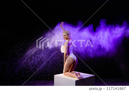 Woman posing with purple particles sprayed in air Woman posing with purple particles sprayed in air 117141867