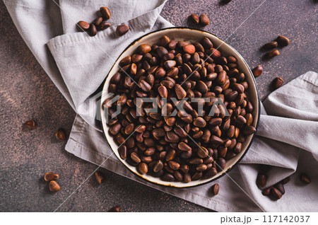 Close up of ripe pine nuts in the shells on a plate on the table top view 117142037