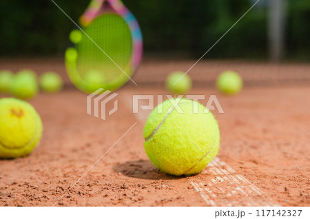 A yellow tennis balls lies on the clay court. A yellow tennis balls lies on the clay court. 117142327