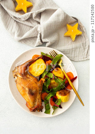 Enjoy a delicious, hearty meal with baked rabbit, roasted potatoes, and carrot salad, combining savory flavors and wholesome ingredients for a nutritious and satisfying dinner 117142580