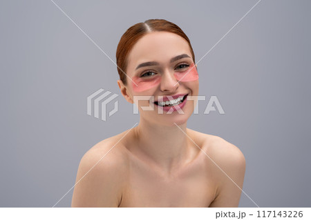 Portrait of a pretty young woman with moisturizing patches under her eyes Portrait of a pretty young woman with moisturizing patches under her eyes 117143226