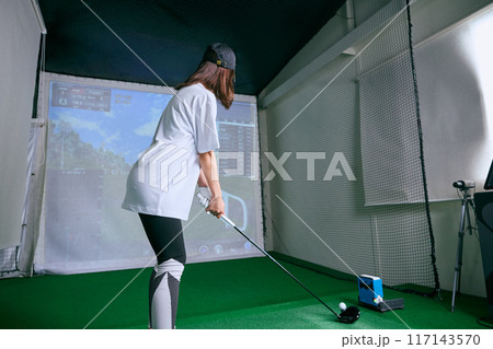 室内ゴルフ練習場で練習をする女性 117143570