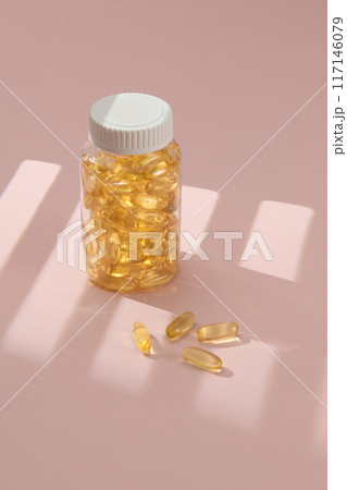 Fish oil supplement capsule in clear plastic jar, which displayed on beige background with shine shadow of window. Fish oil provides omega-3 fatty acids, which necessities for people health 117146079