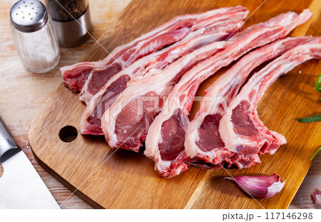 Raw hogget chops on wooden board with arugula and garlic Raw hogget chops on wooden board with arugula and garlic 117146298